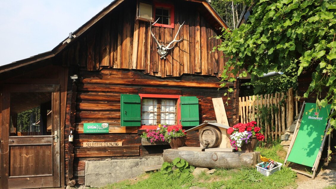 Rustikale Holzhütte mit grünen Fensterläden, Blumen und Getränkestation am Walzkogel. | © Heinz Kaltschmidt