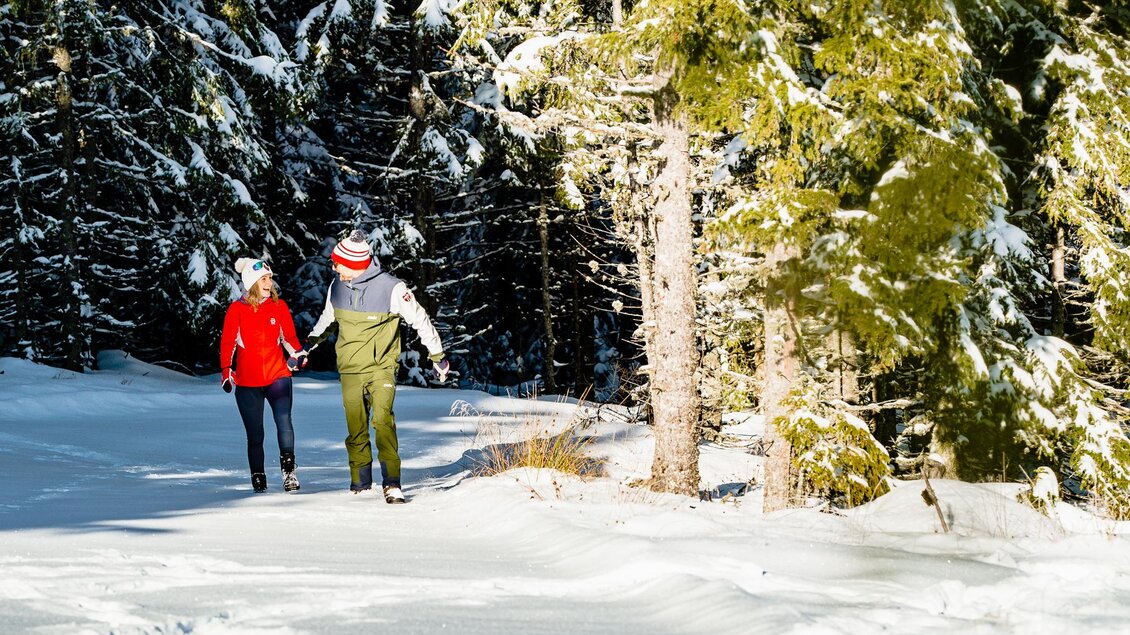Mann und Frau wandern im Winter durch verschneiten Nadelwald am Schöckl bei Graz. | © Regiion Graz-Mias Photoart