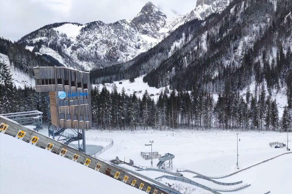 Eine schneebedeckte Skisprungschanze in einer beeindruckenden Berglandschaft. Umgeben von hohen, grünen Bäumen und majestätischen Bergen. | © NAZ Eisenerz