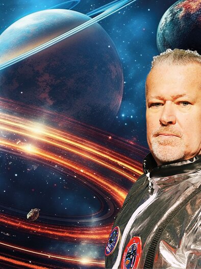 Mike Supancic trägt einen glänzenden, silbernen Raumanzug mit Emblemen, während er vor einem farbenprächtigen, galaktischen Hintergrund mit Planeten und Ringen steht. Der Bildausschnitt vermittelt eine Szene aus dem Weltraum, die mit futuristischem Flair und einer kosmischen Atmosphäre gestaltet ist. | © Lukas Beck