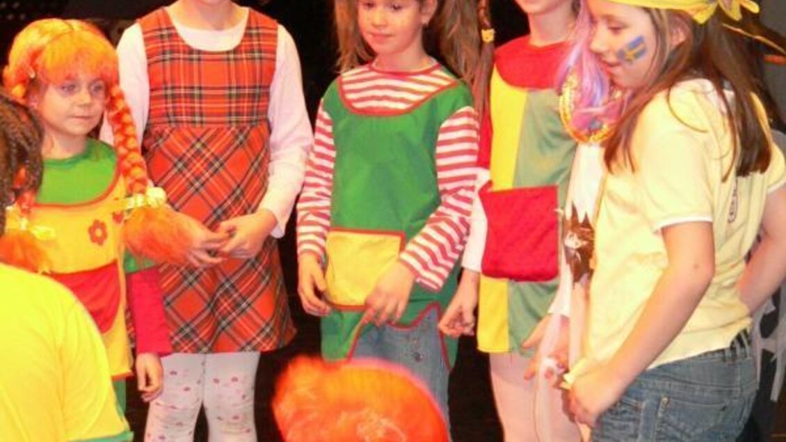 Eine Gruppe von Mädchen in bunten Kostümen steht zusammen auf einer Bühne. Sie haben fröhliche Gesichtsmalerei und zeigen viel Spaß. | © Lederer