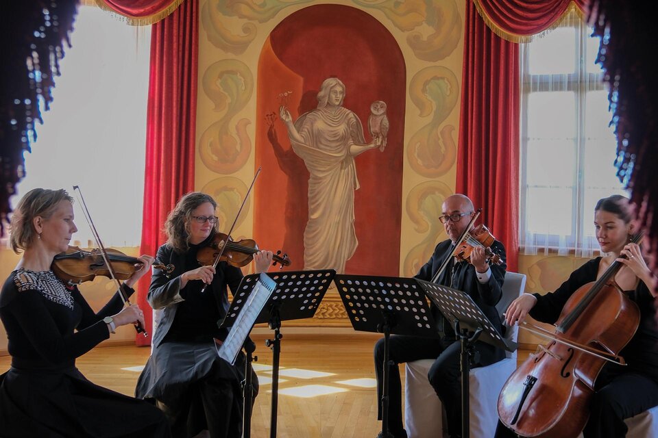 Eine Gruppe von vier Musikern spielt in einem eleganten Raum. Im Hintergrund ist eine beeindruckende Wandmalerei zu sehen. | © Weinschloss Thaller