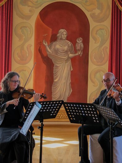 A group of four musicians is playing in an elegant room. In the background, there is an impressive mural. | © Weinschloss Thaller