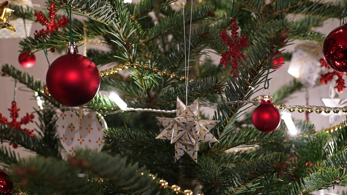 Ein geschmückter Weihnachtsbaum mit roten Kugeln und einem Stern aus Papier. Die Lichter sorgen für eine festliche Atmosphäre. | © Pixabay_felix
