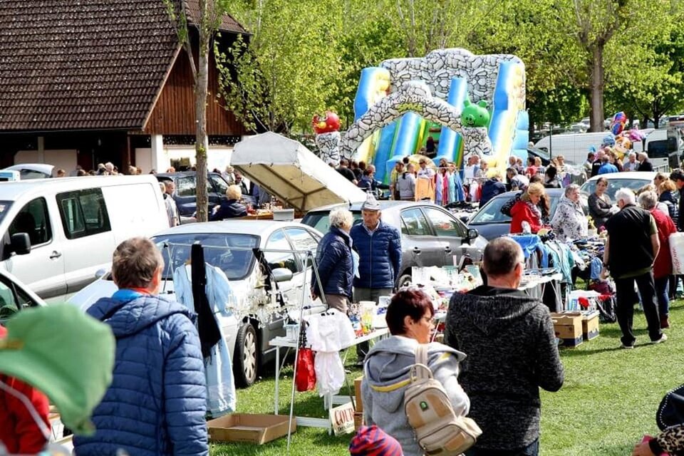 Ein belebter Flohmarkt mit vielen Ständen und Menschen. Im Hintergrund ist eine Hüpfburg zu sehen, die für Kinder steht. | © Kirchmeier
