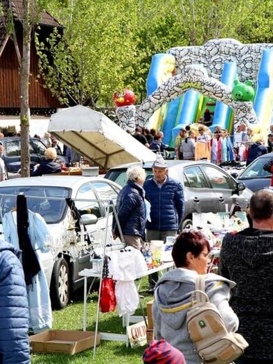 A bustling flea market with many stalls and people. In the background, a bouncy castle is visible, which is meant for children. | © Kirchmeier