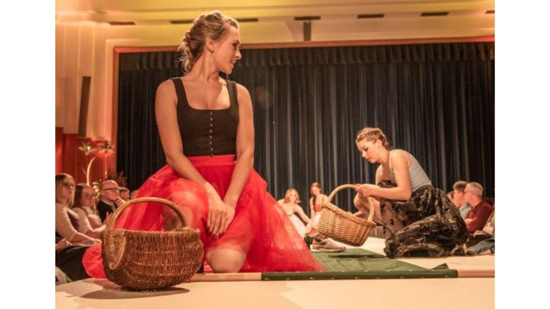 Eine Modenschau mit Models in kreativen Outfits auf der Bühne. Die Zuschauer sitzen gespannt im Hintergrund und beobachten die Darbietung. | © www.narzissenfest.atTSams