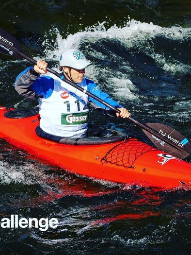 A canoer is paddling in a red kayak on a raging river. Spray and waves surround him in a dynamic competition scene. | © HQ Superphoto