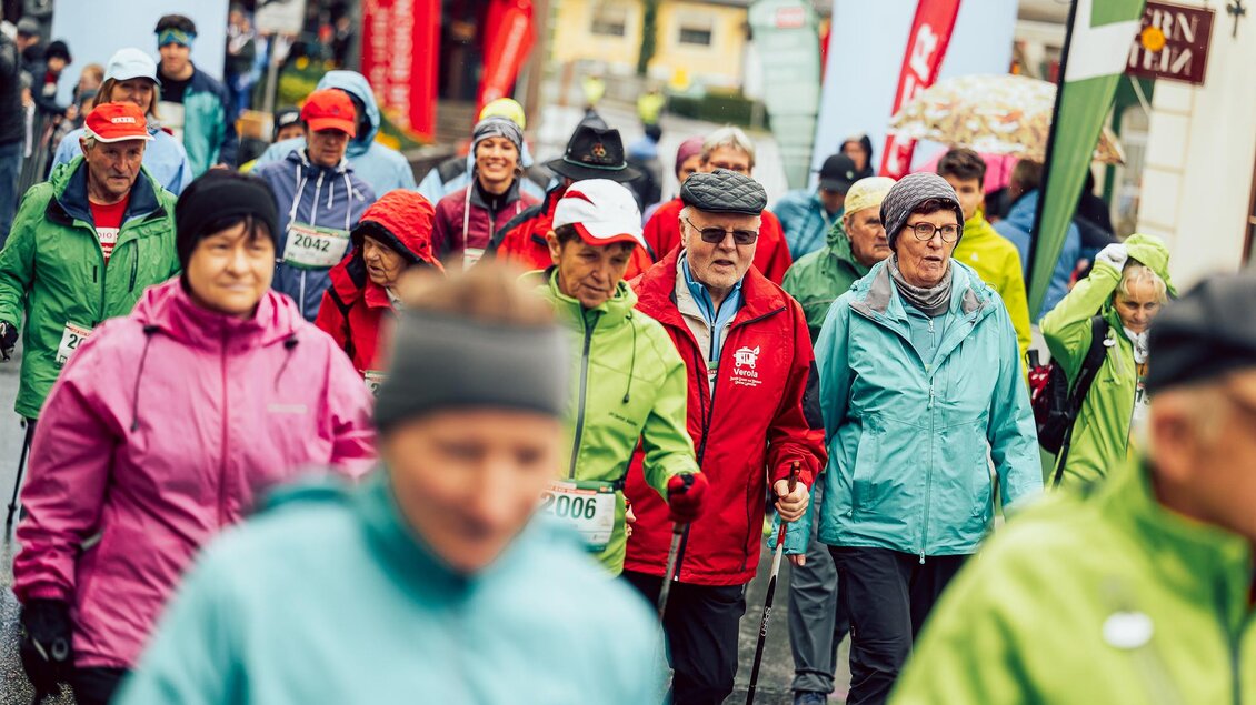Eine Gruppe von Menschen geht in bunten Jacken bei einem Sportevent. Die Teilnehmer wirken motiviert und aktiv.