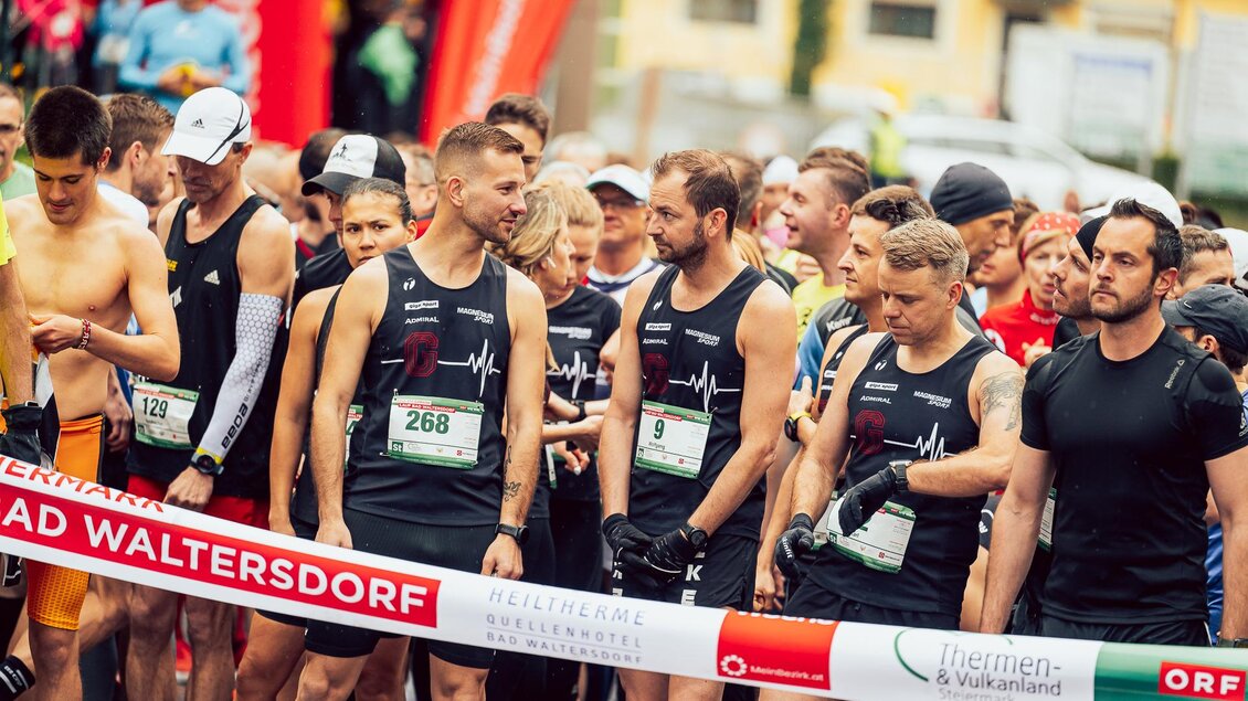 Eine Gruppe von Läufern steht an der Startlinie eines Wettlaufs. Sie tragen sportliche Kleidung und warten auf den Startschuss. | © Hikimus