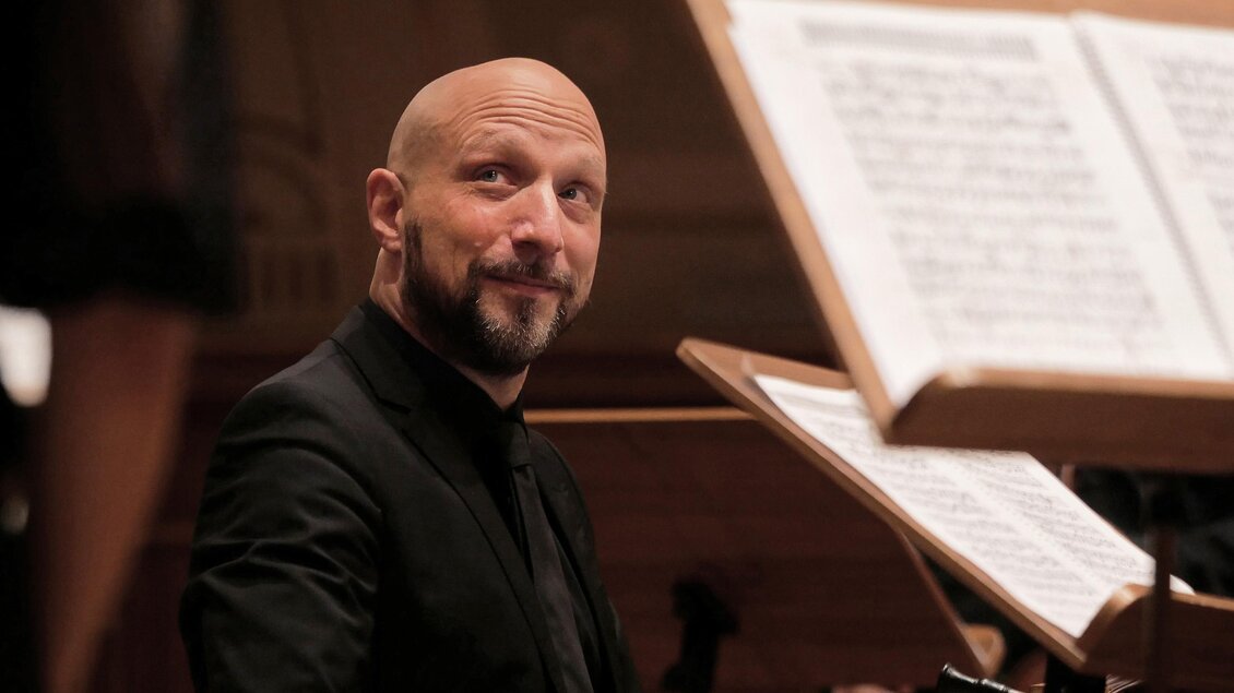 Ein Mann sitzt am Klavier und schaut lächelnd. Notenblätter sind im Vordergrund sichtbar. | © matthias-wagner