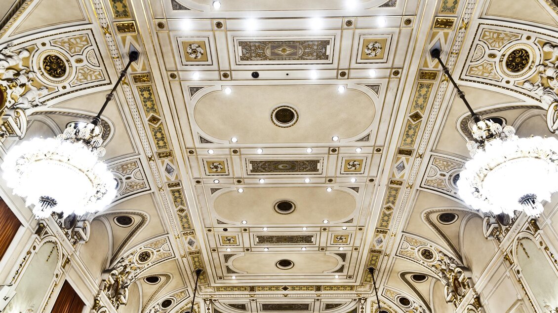 Ein prächtiger Konzertsaal mit einem reich verzierten Deckenmuster und eleganten Kronleuchtern. Die Architektur strahlt Luxus und Stil aus. | © MCG - Werner Krug