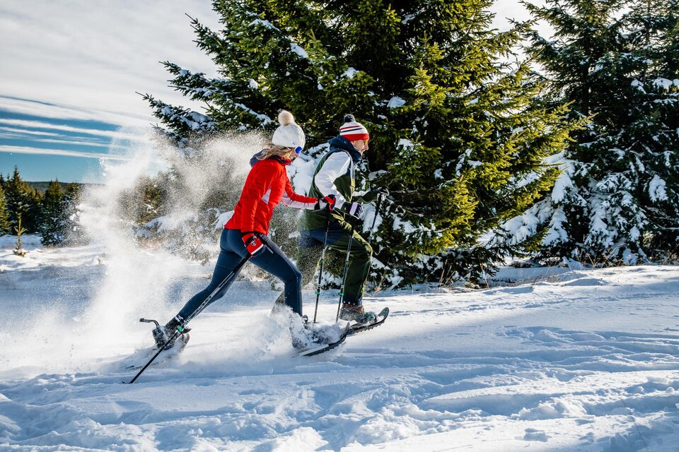 Der Schnee staubt bei der flotten Schneeschuhwanderung des Paares bei herrlichen Sonnenschein.  | © Region Graz-Mias Photoart
