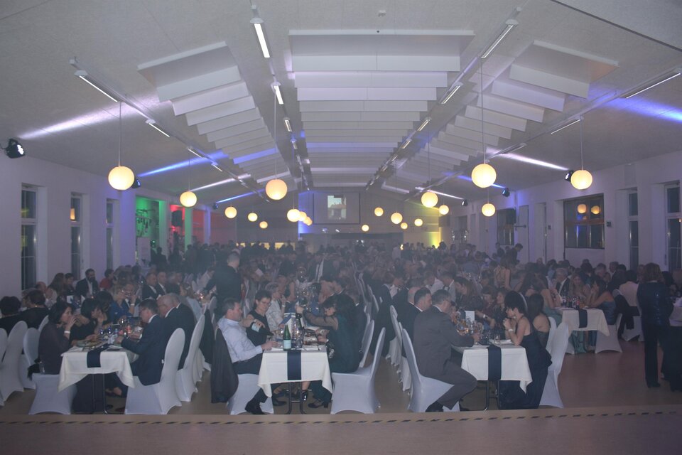 Ein festlicher Saal mit vielen Gästen, die an Tischen sitzen. Die Atmosphäre ist lebhaft mit sanfter Beleuchtung. | © USV St. Anna am Aigen