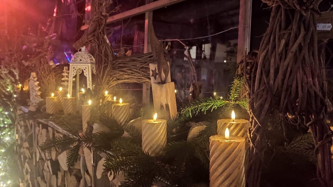 Ein festlich dekorierter Tisch mit brennenden Kerzen und einem natürlichen Arrangement aus Tannenzweigen. Die Atmosphäre ist warm und einladend. | © Stocker Peter