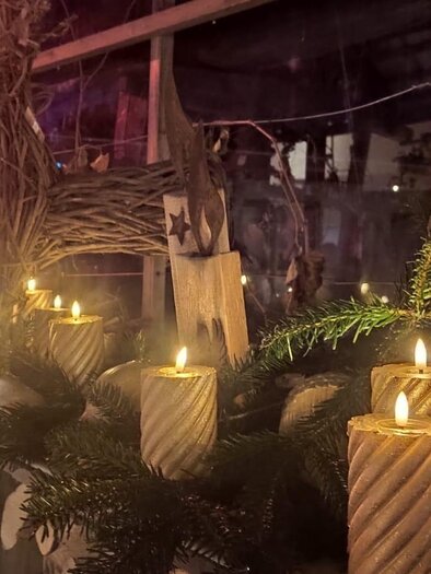 A festively decorated table with burning candles and a natural arrangement of pine branches. The atmosphere is warm and inviting. | © Stocker Peter
