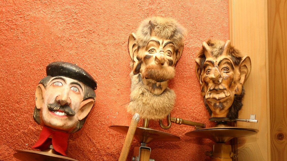 Drei kunstvoll gestaltete Masken hängen an einer Wand. Jede Maske hat ein einzigartiges Design und Gesichtsausdruck. | © Steirisches Volksliedwerk