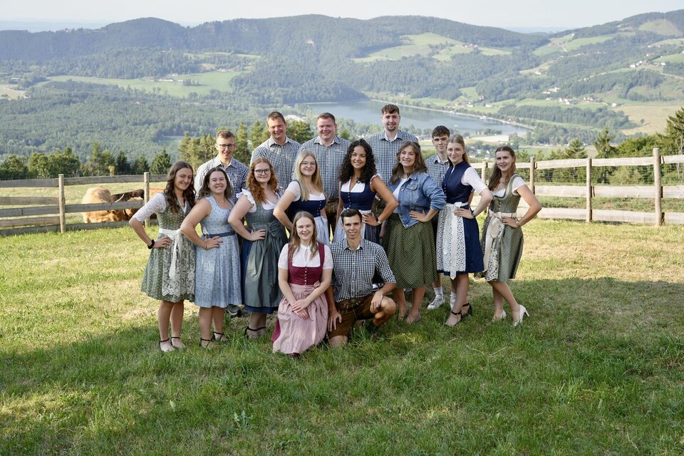 Eine Gruppe von Menschen steht auf einer Wiese mit Blick auf die Berge. Sie tragen traditionelle Kleidung und lächeln in die Kamera. | © Landjugend Stubenberg