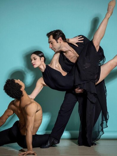 Three dancers in blue dresses and a dancer in black clothing are dancing in an elegant room. In the background, historical paintings can be seen. | © Harald Eisenberger