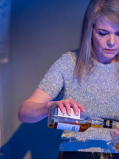 A woman pours alcohol into a glass. The room is dimly lit and has a relaxed atmosphere. | © TV Südsteiermark/StainZeit - Johannes Gellner