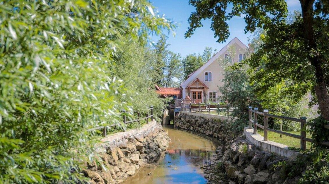Ein ruhiges Haus am Wasser mit einer malerischen Umgebung. Grüne Bäume und ein klarer Himmel schaffen eine entspannte Atmosphäre. | © © Foto De Monte