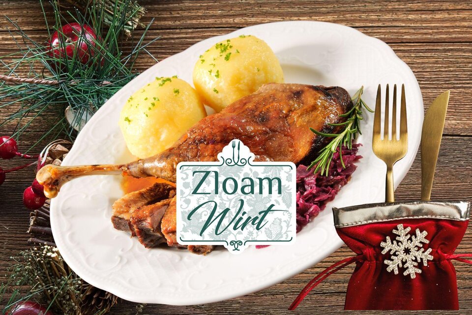 Ein köstliches Gericht mit gebratener Ente, Knödeln und Rotkohl. Im Hintergrund festliche Dekorationen und das Logo von "Zloaam Wirt". | © Narzissendorf Zloam
