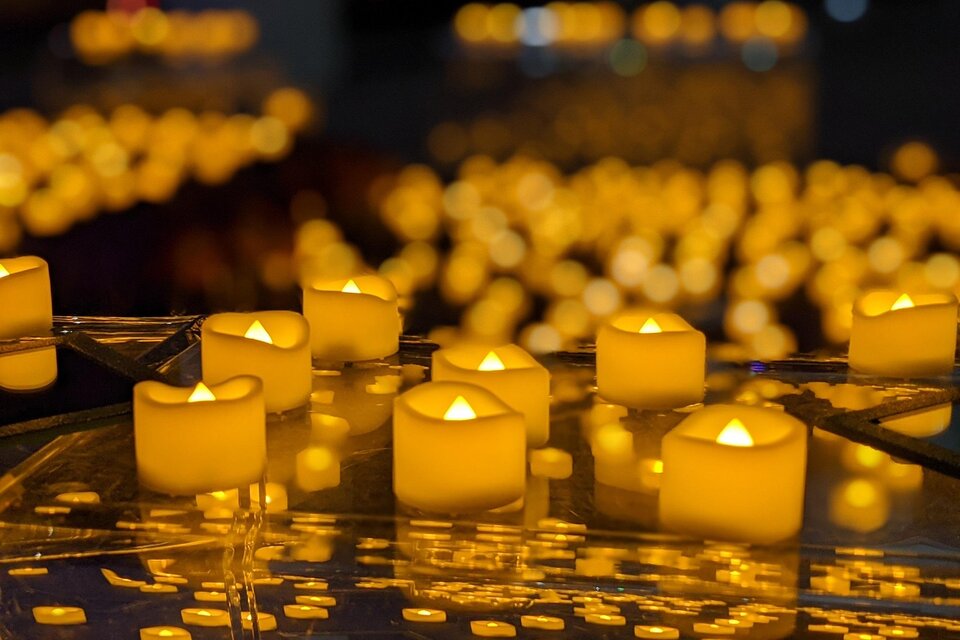 Brennende Kerzen stehen auf glänzenden Parkett, es ist ein Kerzenmeer, die ein warmes Licht spenden im Stefaniensaal in Graz. | © DE.Light Events UG