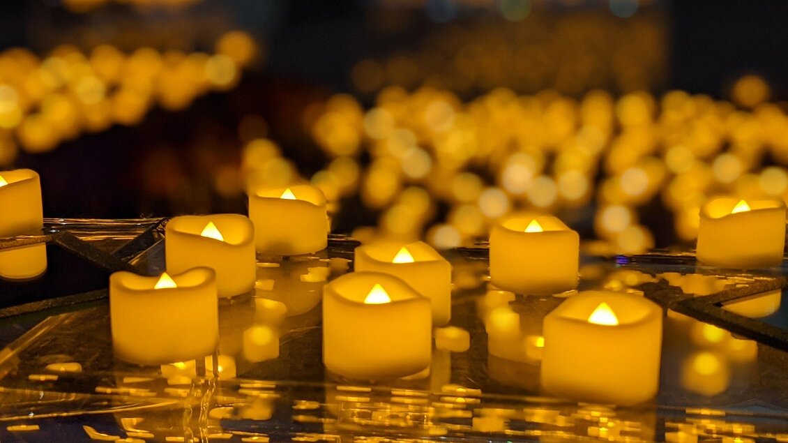 Brennende Kerzen stehen auf glänzenden Parkett, es ist ein Kerzenmeer, die ein warmes Licht spenden im Stefaniensaal in Graz. | © DE.Light Events UG