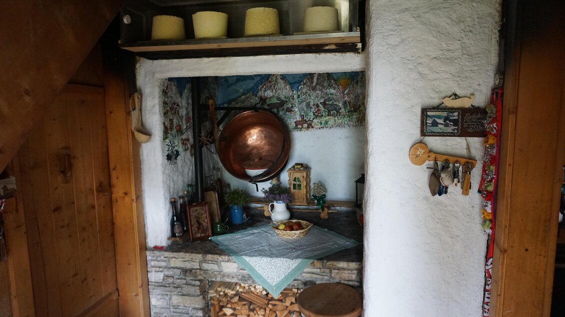 Eine gemütliche Küchenecke mit einer Steinablage und bunten Wandmalereien. Auf dem Tisch steht eine Schüssel mit Obst und ein Kaffeekännchen. | © Naturpark Sölktäler