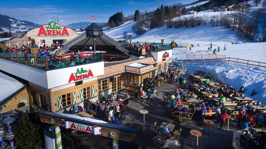 AlmArenA an der Talstation Hauser Kaibling mit großer Sonnenterrasse und Gästen beim Après-Ski im Winter. | © AlmArenA