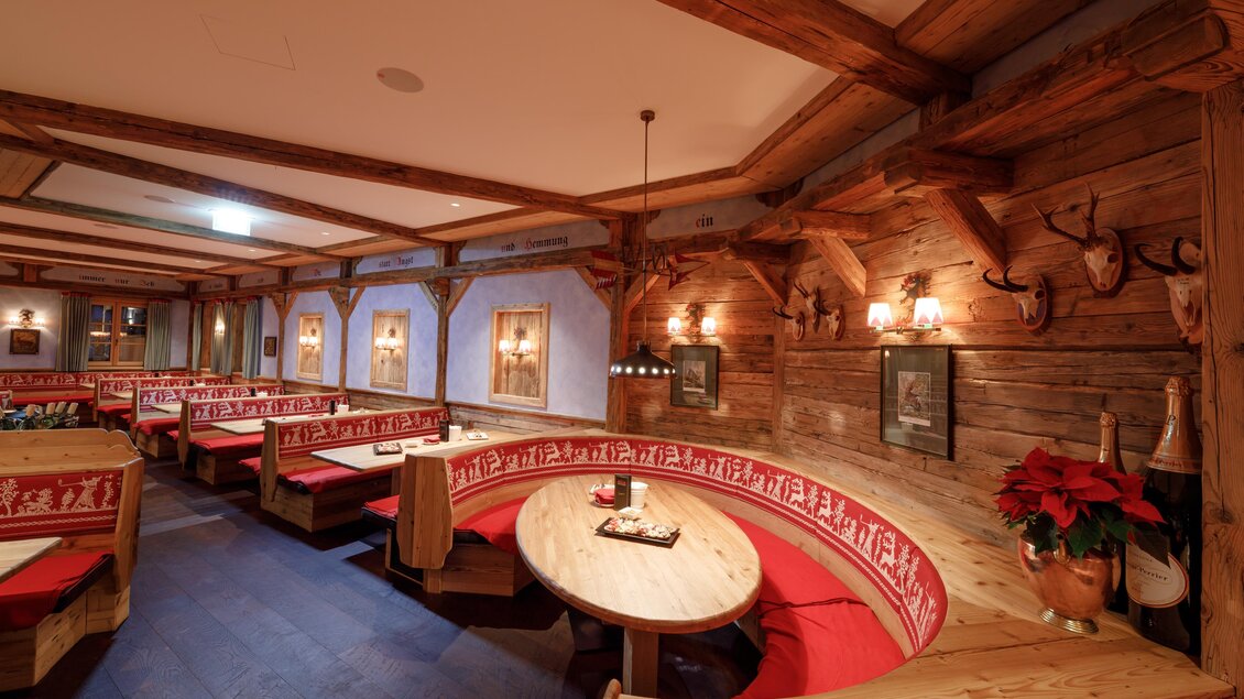 Ein gemütliches Restaurant mit Holzelementen und roten Polsterbänken. Die Wände sind dekoriert und schaffen eine einladende Atmosphäre. | © AlmArenA