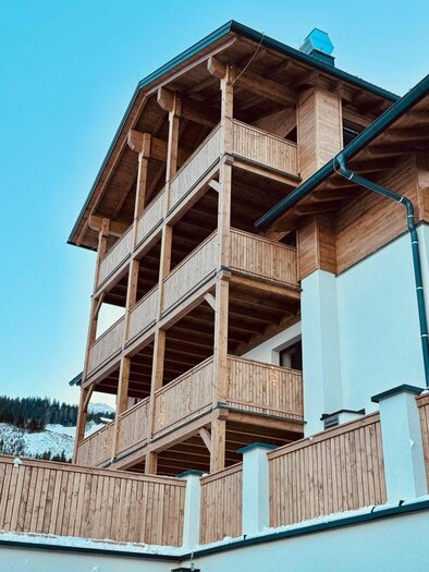 Ein modernes Holzhaus mit mehreren Balkonen und einer klaren Aussicht. Die Fassade besteht aus hellem Holz und harmoniert gut mit der Umgebung. | © Alpenexperience