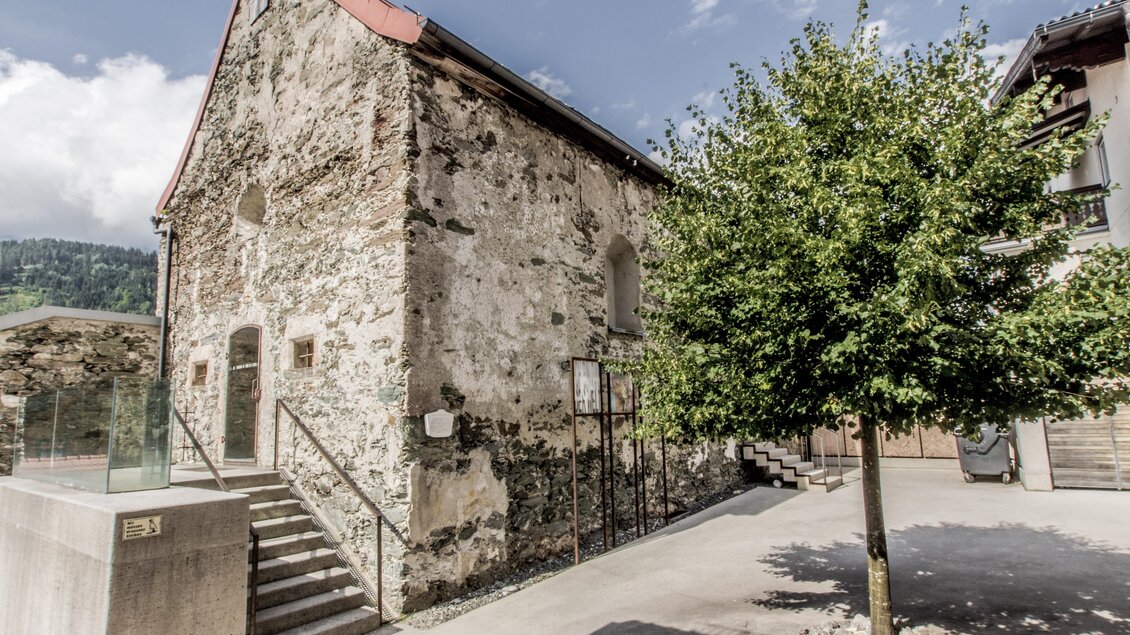 Ein altes, restauriertes Gebäude mit einer zerfallenen Steinfassade und rotem Dach. Ein Baum steht im Vordergrund und ergänzt die grüne Umgebung. | © Gerhard Pilz