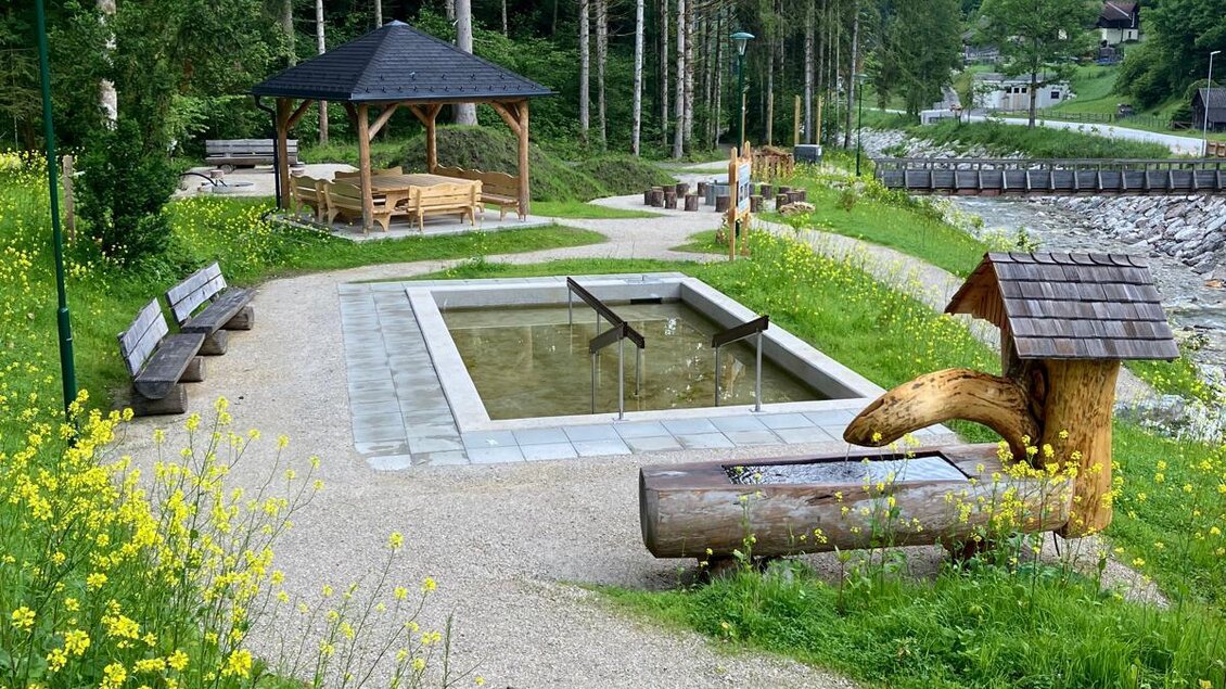 Ein ruhiger Park mit einem kleinen Planschbecken und einer overdachten Sitzgelegenheit. Grüne Wiesen und Bäume umgeben die entspannende Landschaft. | © Nadine Schrempf