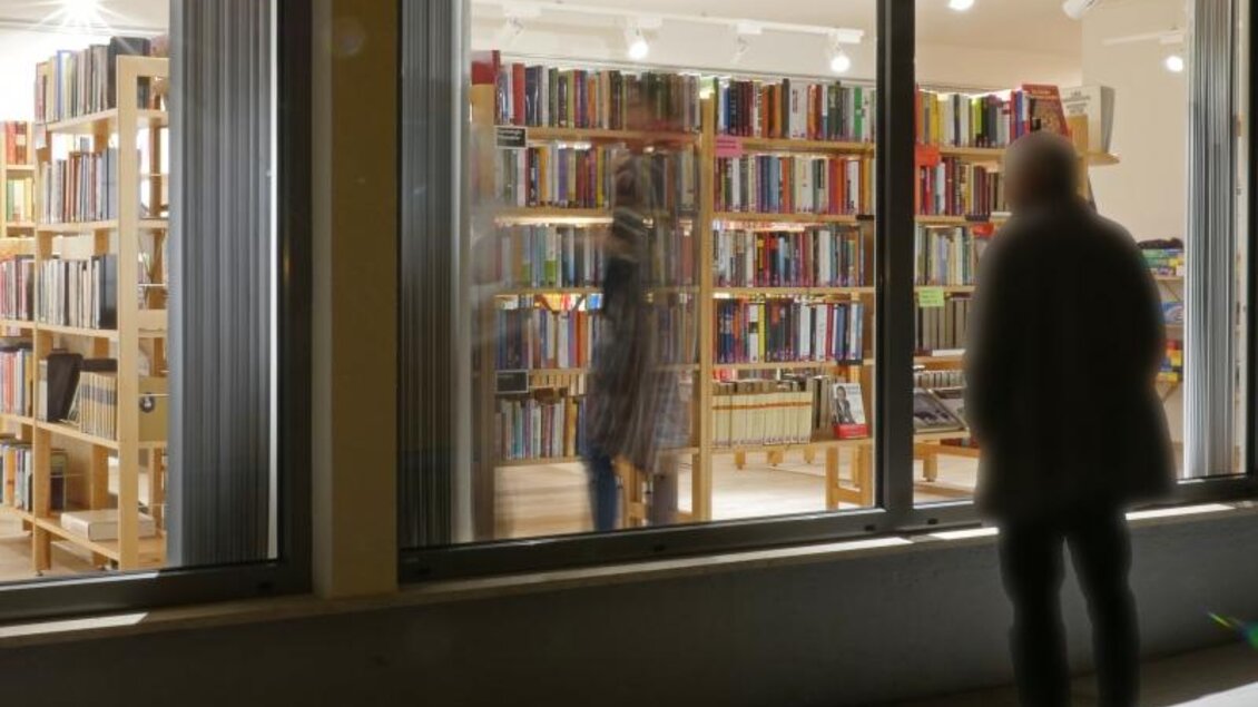 Eine Buchhandlung mit vielen Regalen voller Bücher. Draußen steht eine Person, die durch das Fenster schaut. | © Bücherei Gröbming