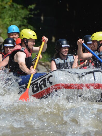 A group of people is navigating a raging river together in an inflatable boat. They are wearing helmets and paddling enthusiastically in the water. | © Werner Berger