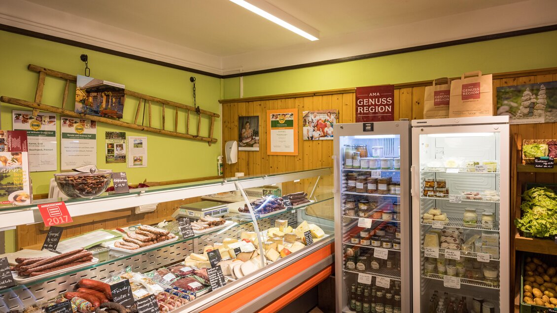 Ein einladender Lebensmittelmarkt mit einer Auslage für Wurst- und Käseprodukte. Im Hintergrund gibt es Kühlschränke mit verschiedenen regionalen Produkten. | © Netzwerk Kulinarik wildbild