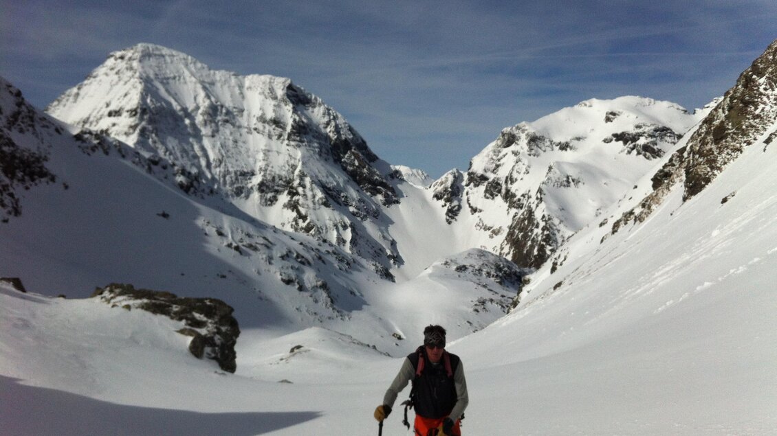 Ein Skifahrer steht in einer schneebedeckten Gebirgslandschaft. Im Hintergrund sind hohe, schneebedeckte Berge und ein klarer Himmel zu sehen. | © Monte-Krah