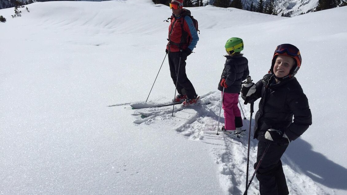 Eine Familie beim Skifahren in einer schneebedeckten Berglandschaft. Die Szene zeigt zwei Kinder und einen Erwachsenen in warmer Winterkleidung. | © Monte-Krah