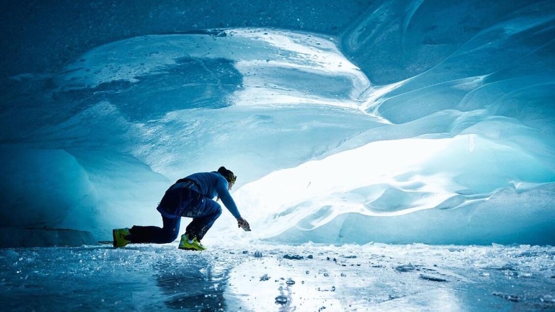 Eine Person erkundet eine beeindruckende Eishöhle. Das Licht strahlt durch das Eis und schafft eine magische Atmosphäre. | © Fischer Sports