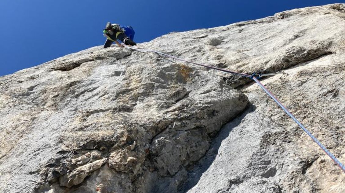 Ein Kletterer erklimmt eine steile Felswand unter einem klaren, blauen Himmel. Seil und Ausrüstung sind gut sichtbar. | © Peter Perhab