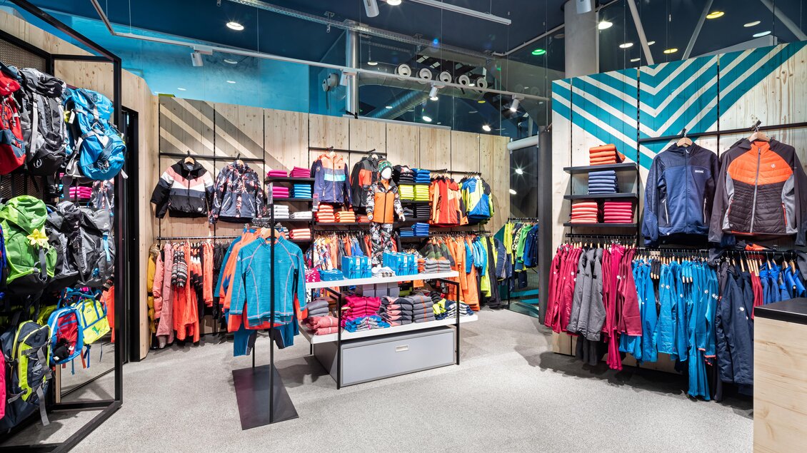Ein moderner Sportbekleidungsladen mit bunten Jacken, Rucksäcken und weiteren Accessoires. Die Regale sind ordentlich angeordnet und präsentieren eine Vielzahl an Farben und Styles. | © Bründl Sports/Christian Wöckinger
