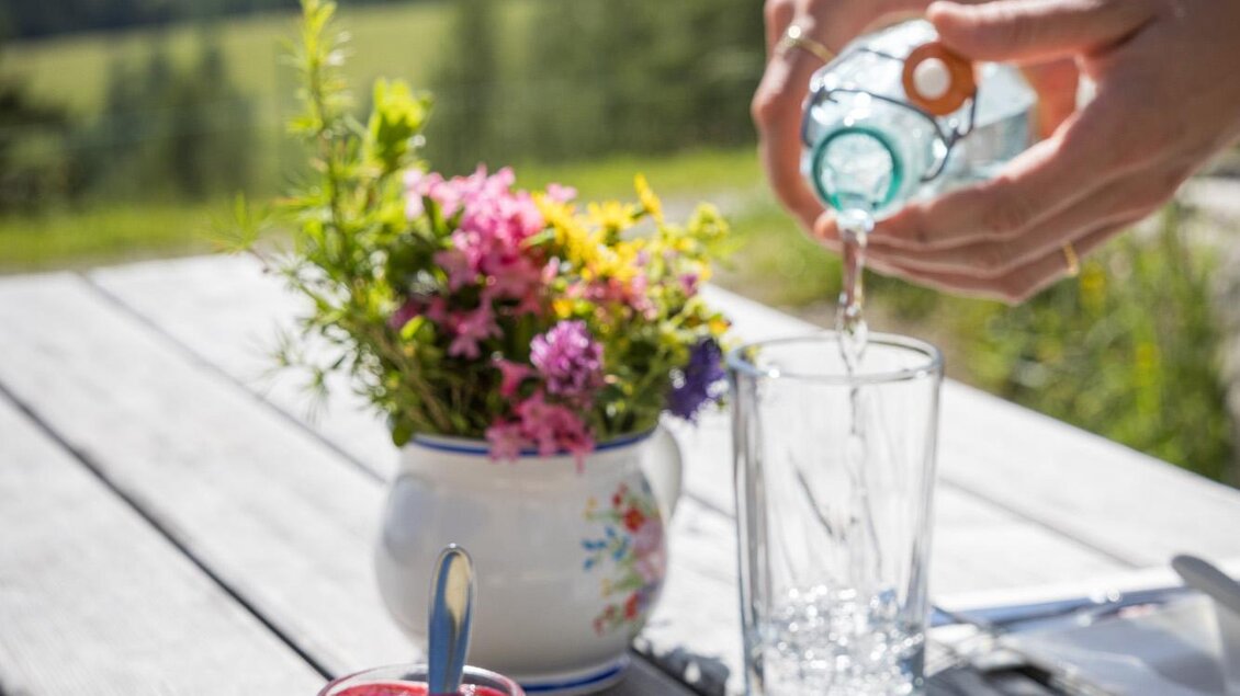 Ein Teller mit frischem Gebäck, serviert mit Marmelade und einem Getränk. Im Hintergrund ist eine schöne Landschaft mit grünen Bergen zu sehen. | © Netzwerk Kulinarik wildbild