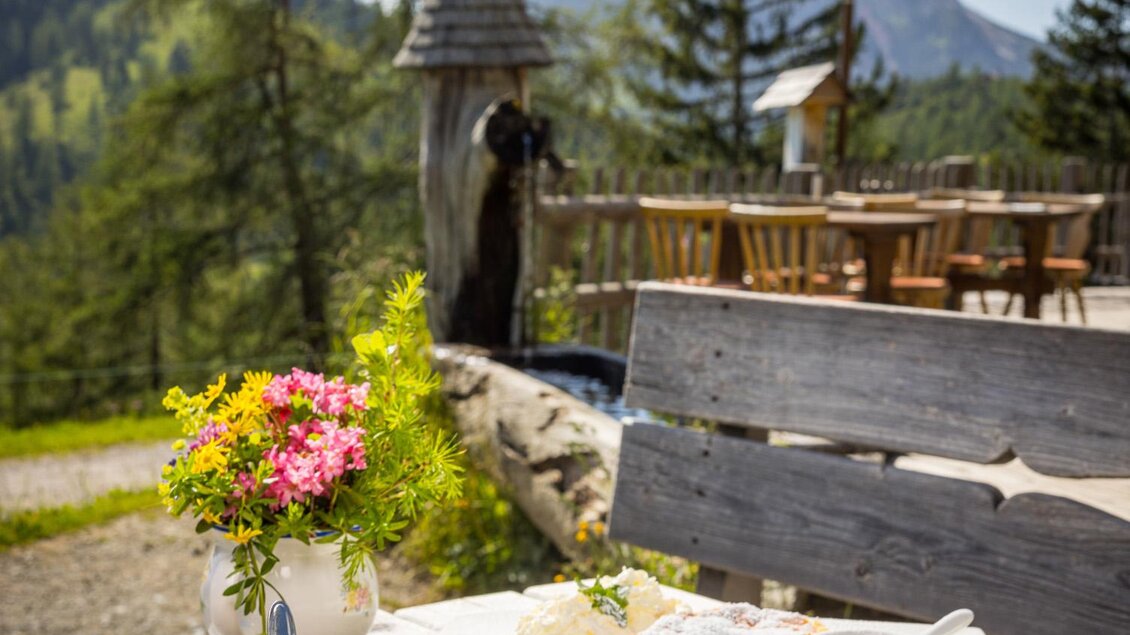 Ein köstliches Frühstück auf einer Terrasse in den Bergen. Auf dem Tisch stehen Süßspeisen, Kaffee und eine blühende Pflanze. | © Netzwerk Kulinarik wildbild