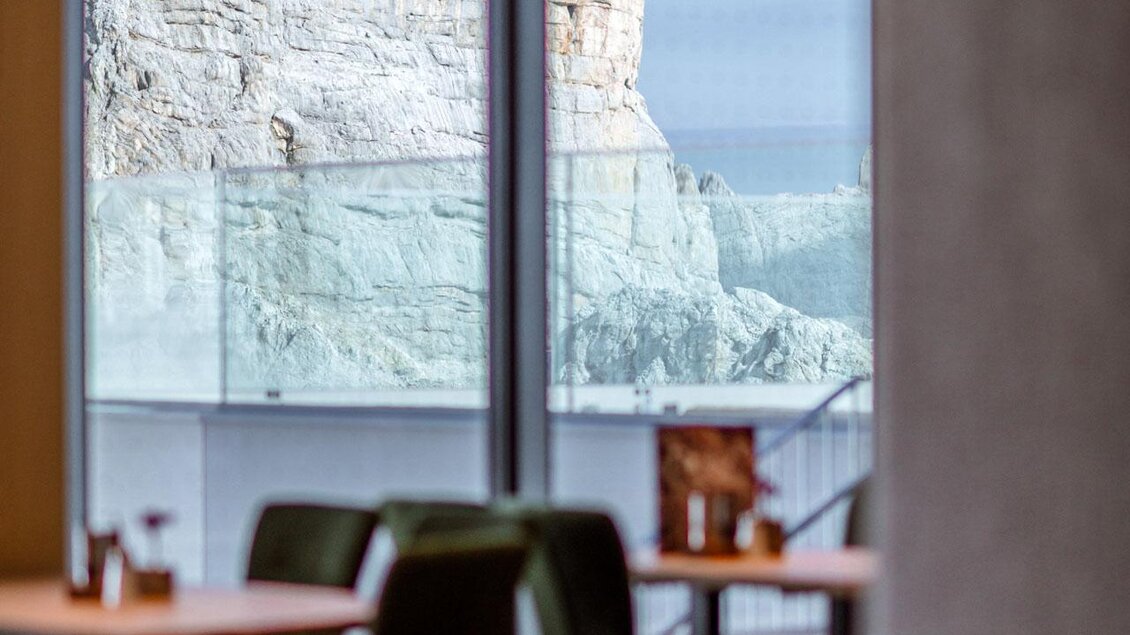 Ein Blick aus einem modernen Café mit großen Fenstern. Im Hintergrund sind Felsen und eine natürliche Landschaft erkennbar. | © Christoph Huber