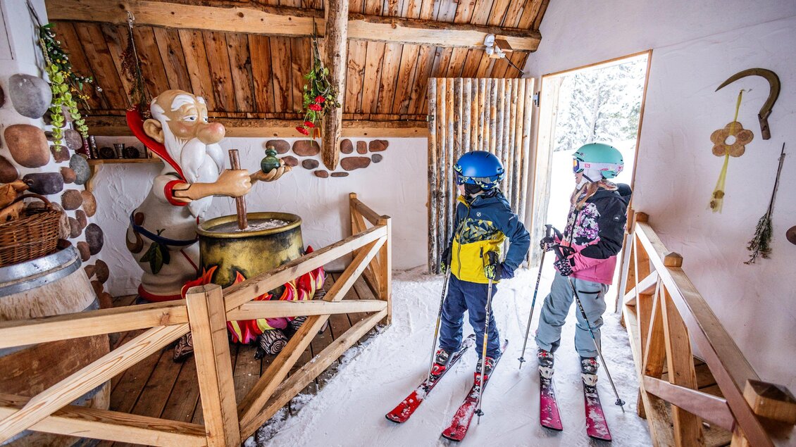 Ein gemütlicher Raum mit Holzdekor, in dem zwei Skifahrer stehen. Hinter ihnen ist eine festliche Weihnachtsdekoration zu sehen, einschließlich einer Figur von Santa Claus. | © Mirja Geh