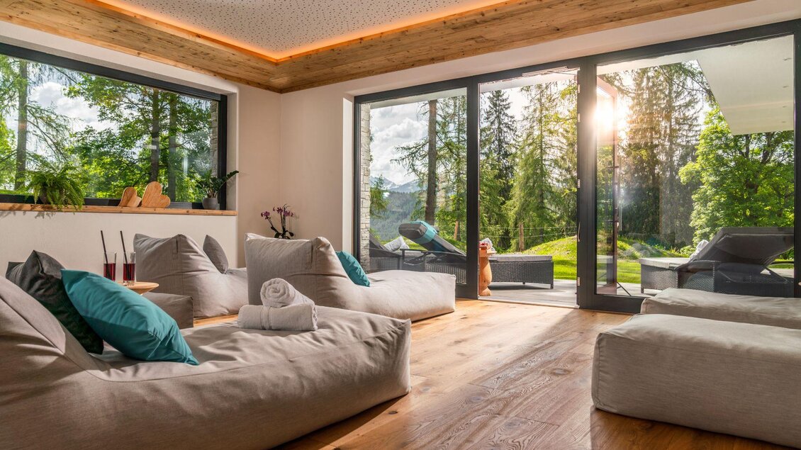 Ein modernes, geschmackvoll eingerichtetes Zimmer mit gemütlichen Sitzsäcken und großen Fenstern. Im Hintergrund sind grüne Bäume und Sonnenschein sichtbar. | © Rösslhof
