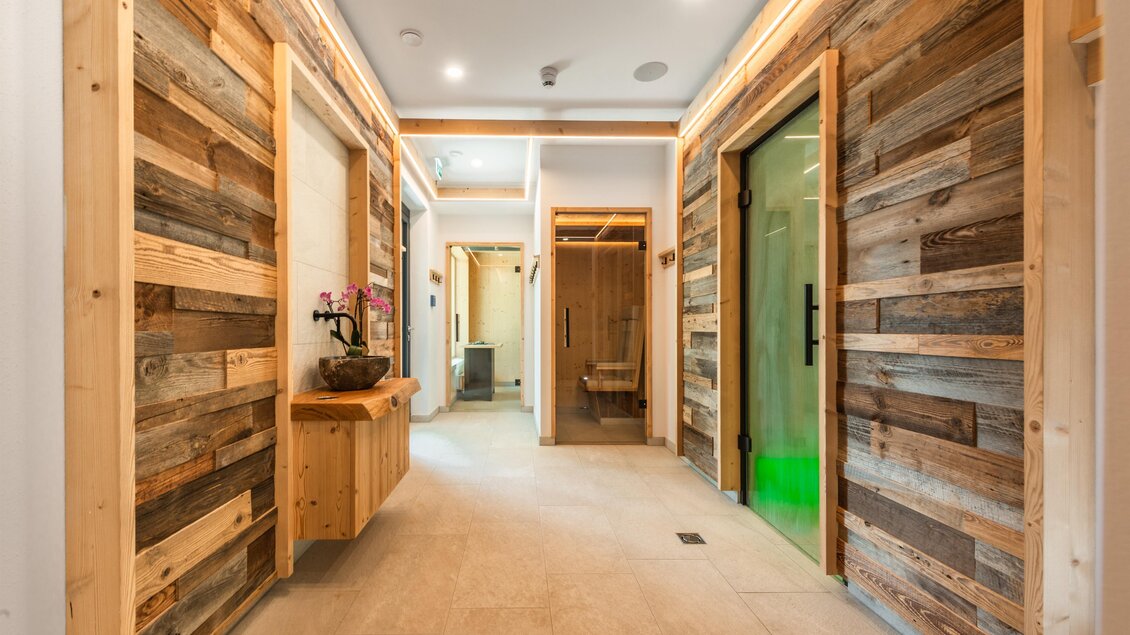 Ein moderner Flur mit Holzverkleidung und hellen Wänden. Am Ende des Flurs sind verschiedene Türen zu sehen, die zu weiteren Räumen führen. | © Rösslhof
