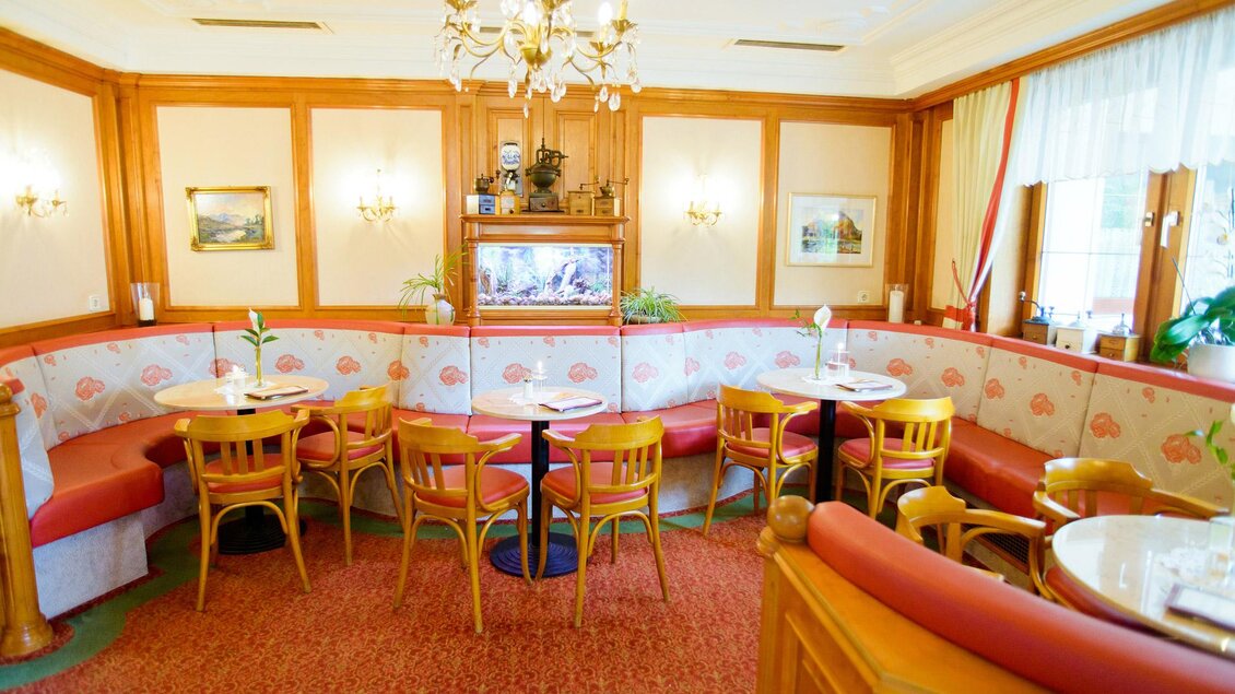 Ein gemütlicher Gastraum mit Holzmöbeln und roten Sitzbänken. Große Fenster sorgen für viel Licht und eine einladende Atmosphäre. | © Dorf Café