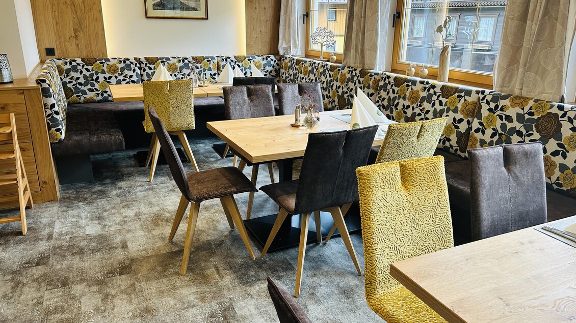 Ein gemütliches Restaurant mit Holzmöbeln und bunten Stühlen. Die Fenster lassen viel Tageslicht herein und schaffen eine einladende Atmosphäre. | © Anna Gasser